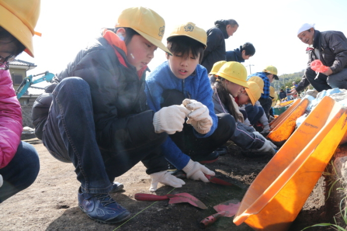 福井小学校の児童たちがスコップを手に発掘体験をする様子の写真