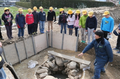 発掘された井戸を見る児童たちの写真