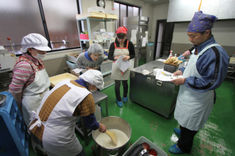 豆腐作りの工程を教わる参加者の写真