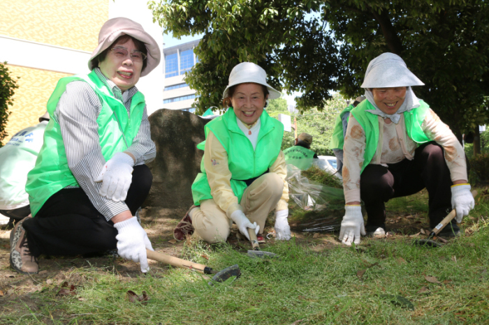 帽子と手袋を身につけ、緑地の清掃をする会員の写真