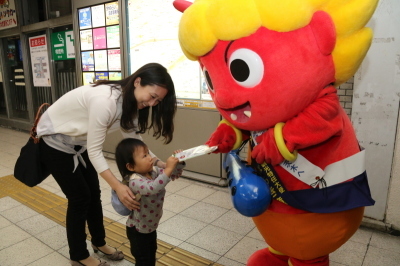 子育て応援キャラクターのいばらっきーちゃんがチラシを親子には配布している様子の写真