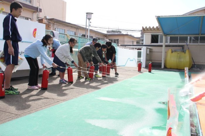 水消火器を使って火の的に水を噴射する子どもたちの写真