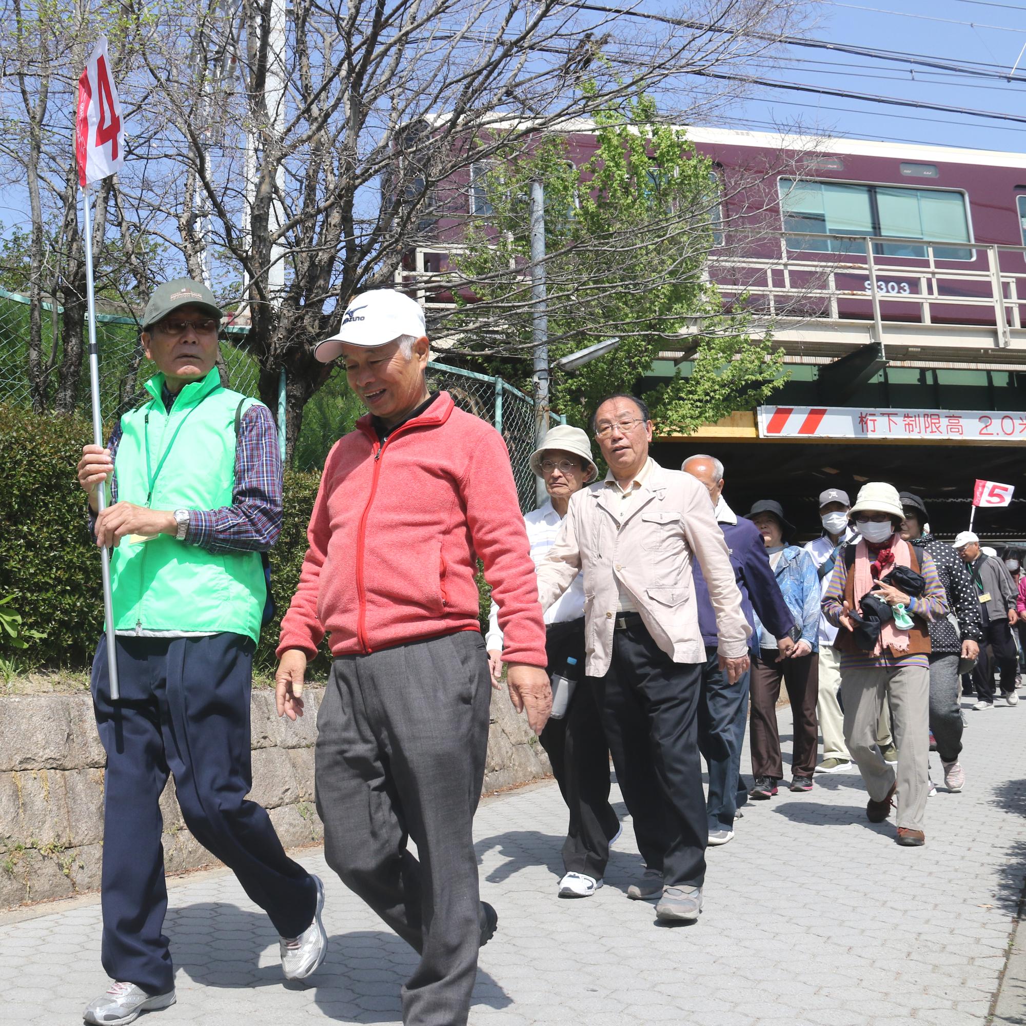 新庄町の阪急高架下を話しながら歩く市老人クラブ連合会の会員