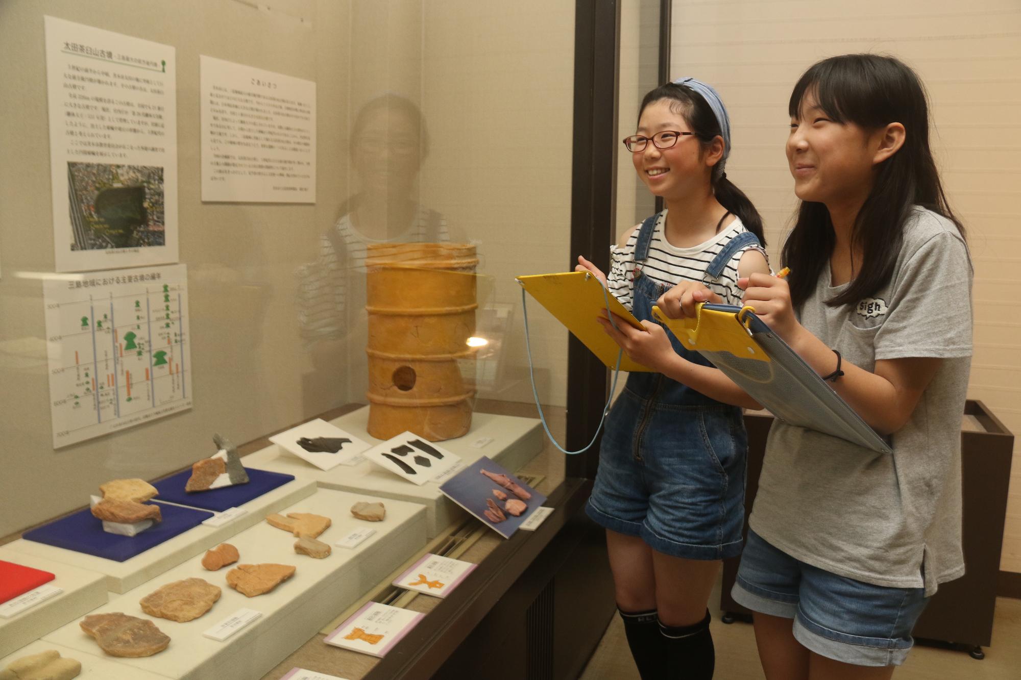 展示を見てメモを取る2人の女子児童