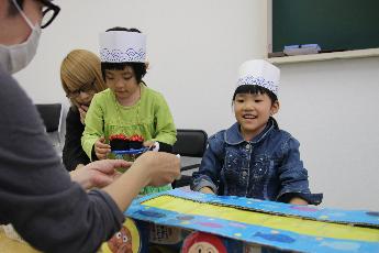 紙で作った回転寿司で遊ぶ子どもたち