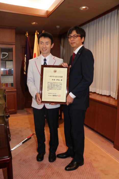 市長室で受賞したキラリいばらき大賞の額入り表彰状を持った茨木市市長と和田選手の画像