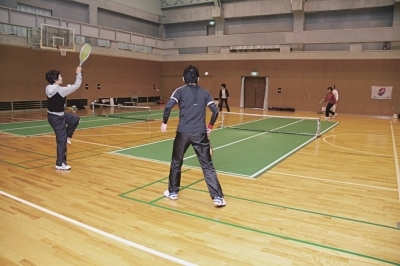 体育館内に設置したコートでバウンドテニスを楽しむ複数の男女